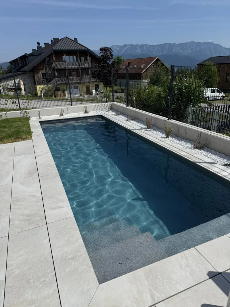 Langes Becken mit anthrazitfarbener Folie, im Hintergrund Berge