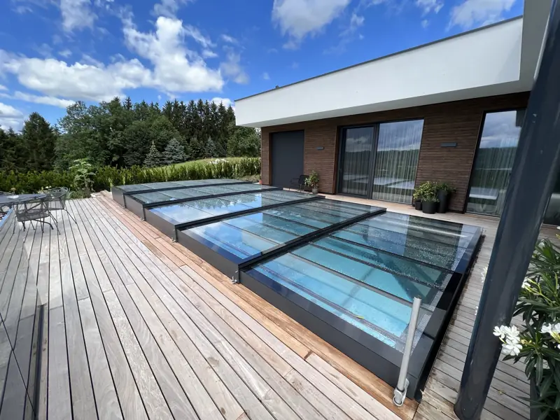 Flache Glas-Schiebeüberdachung über einem Pool an einer Holzterrasse