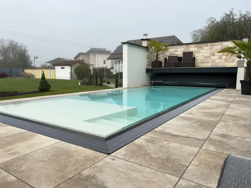 Pool mit heller Auskleidung, Wasser bis zur Kante der Terrassenplatten